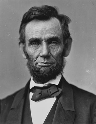 Black and white photo of Abraham Lincoln wearing a tuxedo. He has slightly longer dark hair, with a beard.