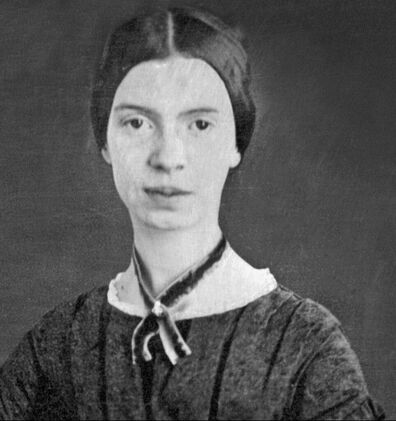 A black and white photo of Emily Dickinson. She is wearing a velvet choker necklace, dress with ruffle neckline, and her dark hair pulled back in a low hairstyle. 